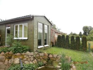 a small house with a stone wall in the yard at Rekreační chatka / Tiny House in Františkovy Lázně