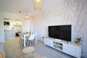 sala de estar con TV y mesa con sillas en Impresionante apartamento con piscina en Sanxenxo, en Sanxenxo