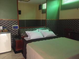 een slaapkamer met een bed met een groen hoofdeinde bij Impérium Inn Motel (Adult Only) in Nova Ponte