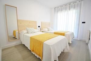 Un dormitorio con dos camas y un gran espejo. en GALIHOST - Impresionante apartamento con piscina en Sanxenxo, en Sanxenxo 19 fotos más