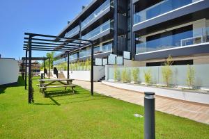 un edificio con un banco en el césped delante de él en GALIHOST - Impresionante apartamento con piscina en Sanxenxo, en Sanxenxo