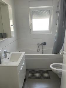 un bagno con vasca, lavandino e finestra di Apartmani Matko a Nin Altre 49 foto