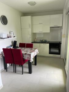 una cucina con tavolo con sedie rosse e una cucina con armadietti bianchi di Apartmani Matko a Nin