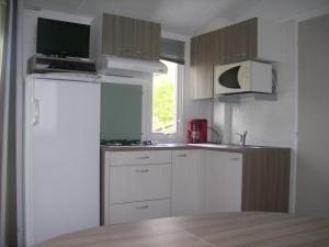 Elle comprend une petite cuisine avec un réfrigérateur blanc et une fenêtre. dans l'établissement Camping Val de Boutonne, à Saint-Jean-dʼAngély