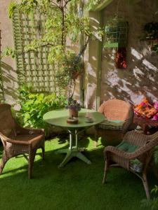 une terrasse avec une table, des chaises et une plante dans l'établissement Le 1930, chambres d’hôtes de charme, à Cosne Cours sur Loire