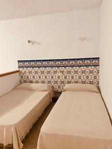 een kamer met 2 bedden en een muur bij HOSTAL LA CAÑADA RUIDERA in Ossa de Montiel