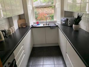 a kitchen with black counter tops and a sink at Georgian 2 Bedroom Apartment in Edinburgh
