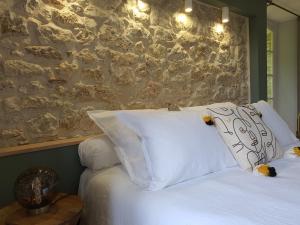 een bed met witte kussens en een stenen muur bij LE MOULIN DE SALAZAR in Montbarla