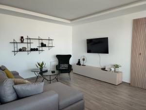 een woonkamer met een bank en een tv aan de muur bij VagiaNa apartment Διαμέρισμα κοντά στο αεροδρόμιο in Antimácheia