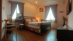 a bedroom with a bed and a desk and two windows at 楓林288 Maple 288 B&B in Jian
