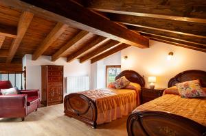 a bedroom with two beds and a chair at La casita de susa en mazcuerras in Villanueva de la Peña