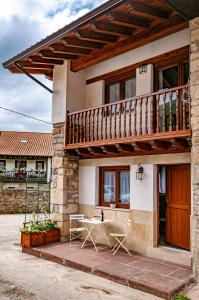 a house with a balcony and a table and chairs at La casita de susa en mazcuerras in Villanueva de la Peña