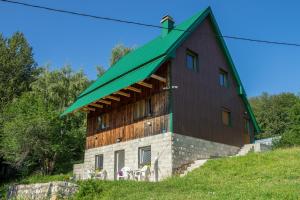 une grande maison avec un toit verdoyant sur une colline dans l'établissement Apartments Stevovic, à Žabljak
