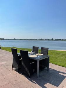 een tafel met vier stoelen naast het water bij Luxe chalet direct aan het water met strand in Lith