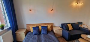 a bedroom with a blue bed and a couch at Apartament Hexagon nr 21 in Grzybowo