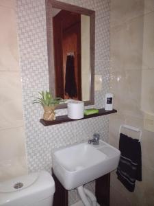 a bathroom with a sink and a toilet and a mirror at Cabaña OHANA ALVORADA -BARRA CHUY BRASIL in Chuy