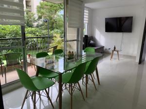 a dining room with a glass table and green chairs at Mango Home in Ricaurte