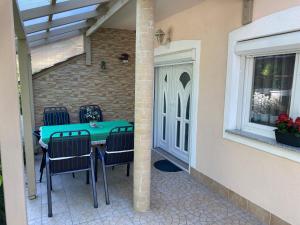 eine Terrasse mit einem Tisch und Stühlen neben einem Fenster in der Unterkunft Sommer Ferienhaus in Balatonszárszó