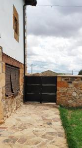 uma porta de garagem preta num edifício com uma parede de pedra em Casa del Medio em Fuentecantos