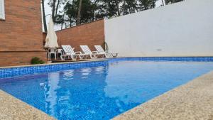 a swimming pool with two chairs and a umbrella at Pinheiro Manso in Apúlia