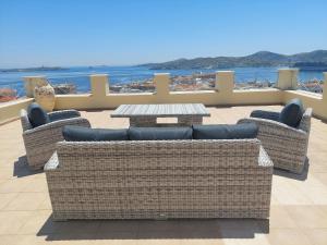 three wicker chairs and a table on a balcony at Hermes Penthouse in Ermoupoli