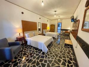 Hotel Vitorina Cholula في تشولولا: غرفة فندقية بسريرين واريكة