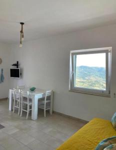 une salle à manger blanche avec une table et une fenêtre dans l'établissement STILL HOUSE, à San Nicola Arcella