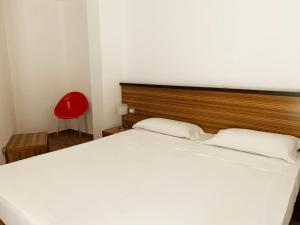 - une chambre avec un lit blanc et une chaise rouge dans l'établissement Nuraghe Apartments, à Teulada