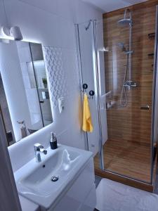 a white bathroom with a shower and a sink at Apartament Luxusowe Karkonosze in Jelenia Góra