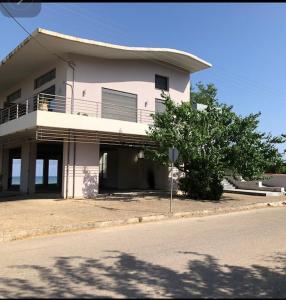 una casa bianca con balcone sul lato di una strada di Maisonette by the sea a Katakolo