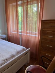 a bedroom with a bed and a dresser and a window at Apartamentai Palangos Centre in Palanga