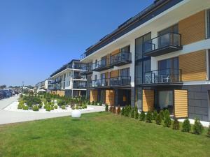 apartamentowiec z trawnikiem przed nim w obiekcie Apartament z basenem i klimatyzacją w Sarbinowie
