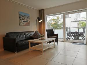 sala de estar con sofá de cuero negro y mesa en Neymeer, en Norderney