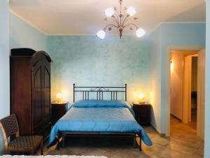 a bedroom with a bed with blue sheets and a chandelier at Agriturismo CuoreLieto del Cilento in Corleto Monforte