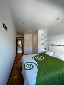a bedroom with a large bed with a green blanket at Gijón del alma in Gijón