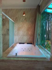 La salle de bains est pourvue d'une grande baignoire et d'une fenêtre. dans l'établissement Pousada Kaetê, à Parati