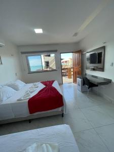 Pousada e Restaurante Altas Horas Beach في إيتابيبوكا: غرفة نوم بسرير ومكتب وتلفزيون