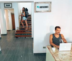 a man sitting at a counter with a laptop at Aji Hostel in Santiago