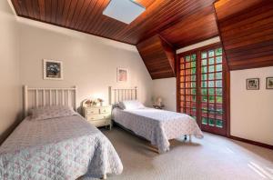 a bedroom with two beds and a wooden ceiling at Suítes Villa Panorama in Campos do Jordão