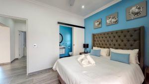 a bedroom with a large bed with blue walls at Caribbean Estate Supreme by Top Destinations Rentals in Port Edward