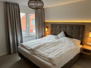 a bedroom with a large bed with white sheets at Haus Antina in Borkum