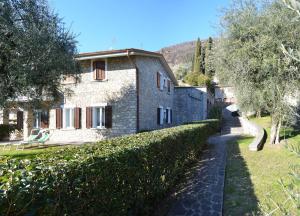 a stone house with a hedge next to a building at Casa Marisa in Gargnano