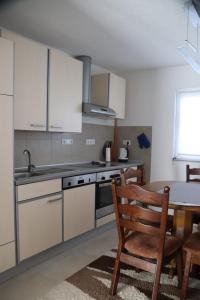 a kitchen with white cabinets and a table and a dining room at Holiday Home Smile in Bihać