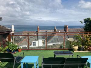 a patio with tables and chairs and a view of the ocean at Modern studio apartment with outstanding views, sleeps 2 in Newlyn