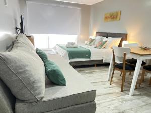 ein Wohnzimmer mit einem Sofa, einem Bett und einem Tisch in der Unterkunft Acqua Apartments Bariloche in San Carlos de Bariloche