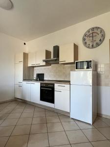 a kitchen with white appliances and a clock on the wall at SeaView Apartments in Koper