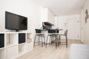 a living room with a flat screen tv and bar stools at Aveiro CityVenice in Aveiro
