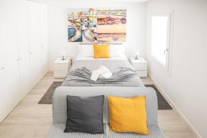 a white bedroom with a large bed with yellow pillows at Aveiro CityVenice in Aveiro
