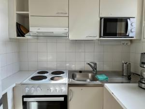 Una cocina blanca con estufa y fregadero. en Rovaniemi budget travels, en Rovaniemi