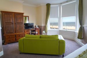 a living room with a green couch and a window at The Royal Hotel in Whitley Bay